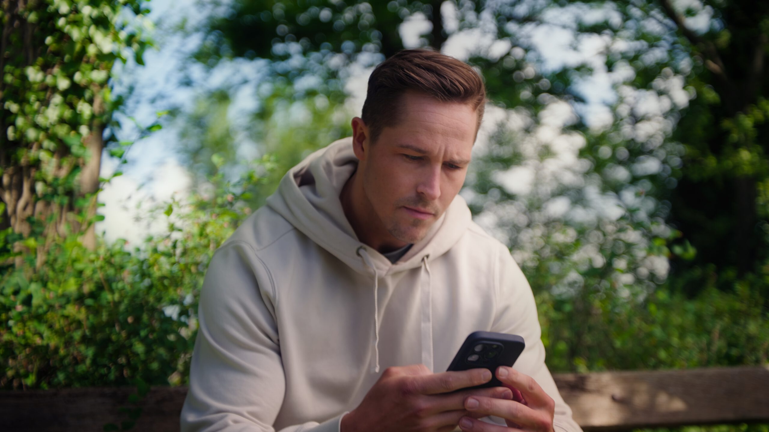 Man op mobiel op een parkbankje voor promotiefilm
